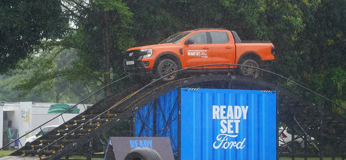 Ford Ranger màu cam trên cầu dốc thép cạnh biển hiệu Ready Set Ford tại khu lái thử